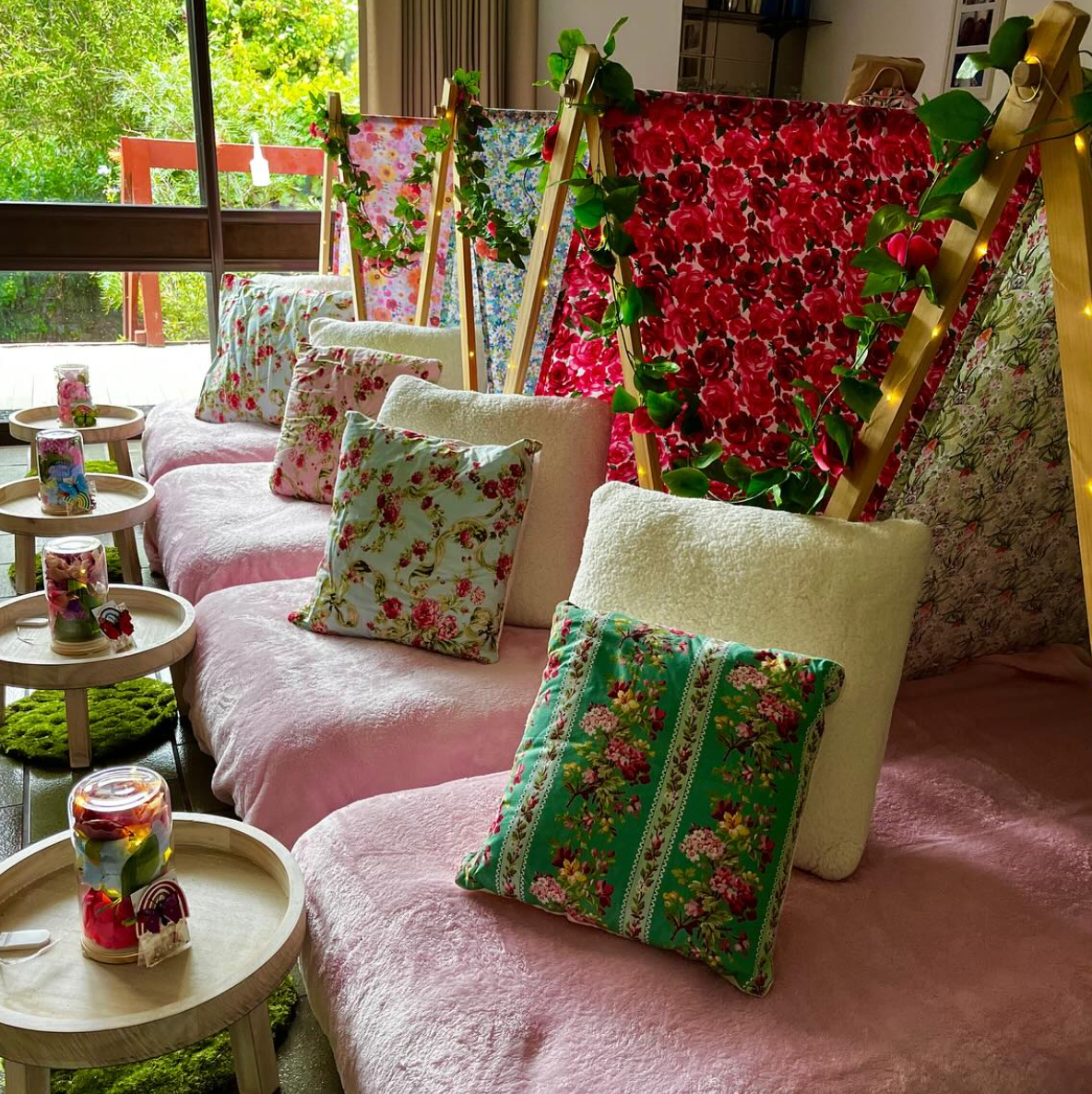 Floral-themed teepee party setup with pink and purple colors, floral pillows, and flowers for the ultimate glamping party experience for kids and girls.