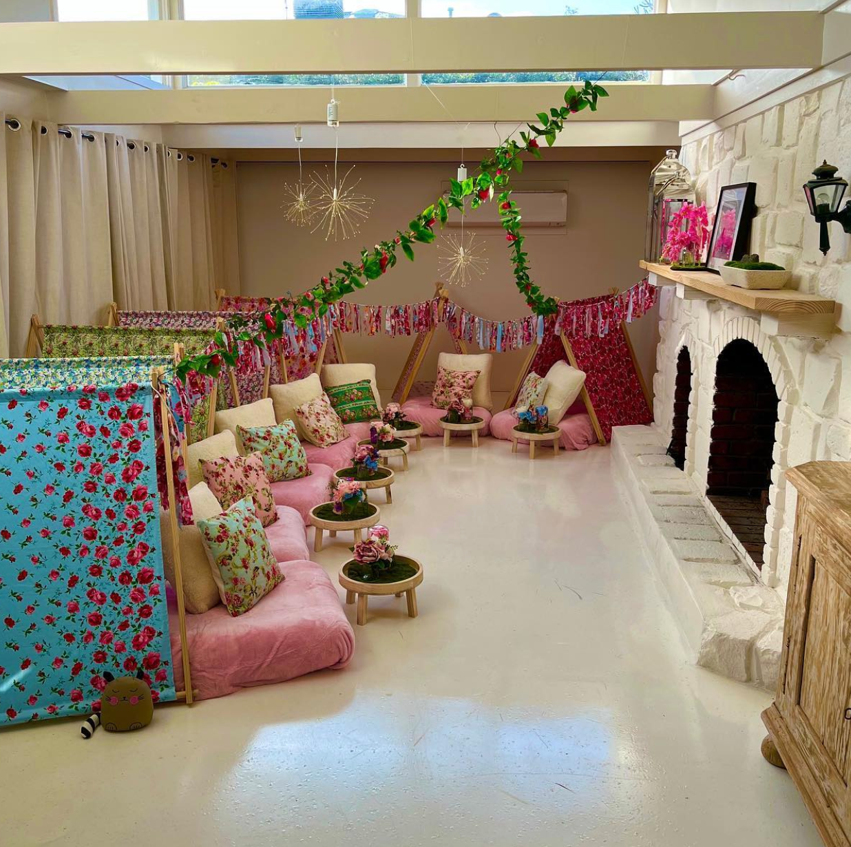 Seven (7) colourful cute teepees with bunting, pink blanket, and twinkle lights set up for a luxury indoor slumber party in Melbourne