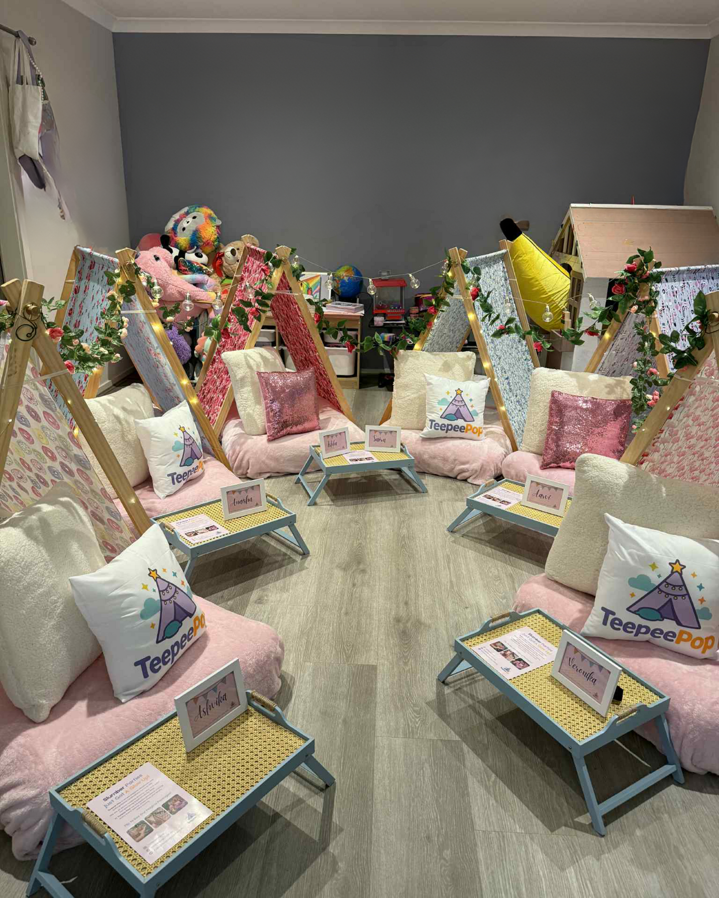 Six (6) colourful cute teepees with bunting, pink blanket, and twinkle lights set up for a luxury indoor slumber party in Melbourne