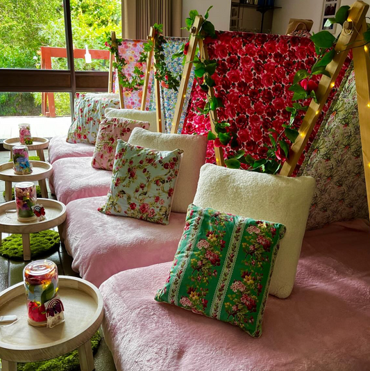 Floral-themed teepee party setup with pink and purple colors, floral pillows, and flowers for the ultimate glamping party experience for kids and girls.