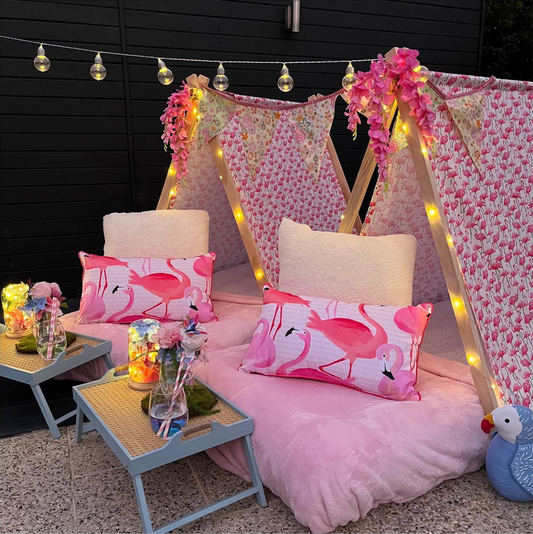 Outdoor glamping tent with cozy bedding, lanterns, and flamingo themed decor for a luxury kids’ glamping experience