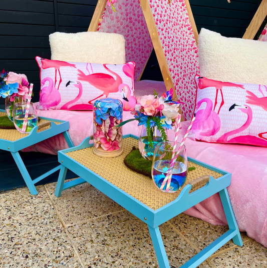 Wooden breakfast tray with glass of water and flowers, set inside a teepee for a cozy sleepover
